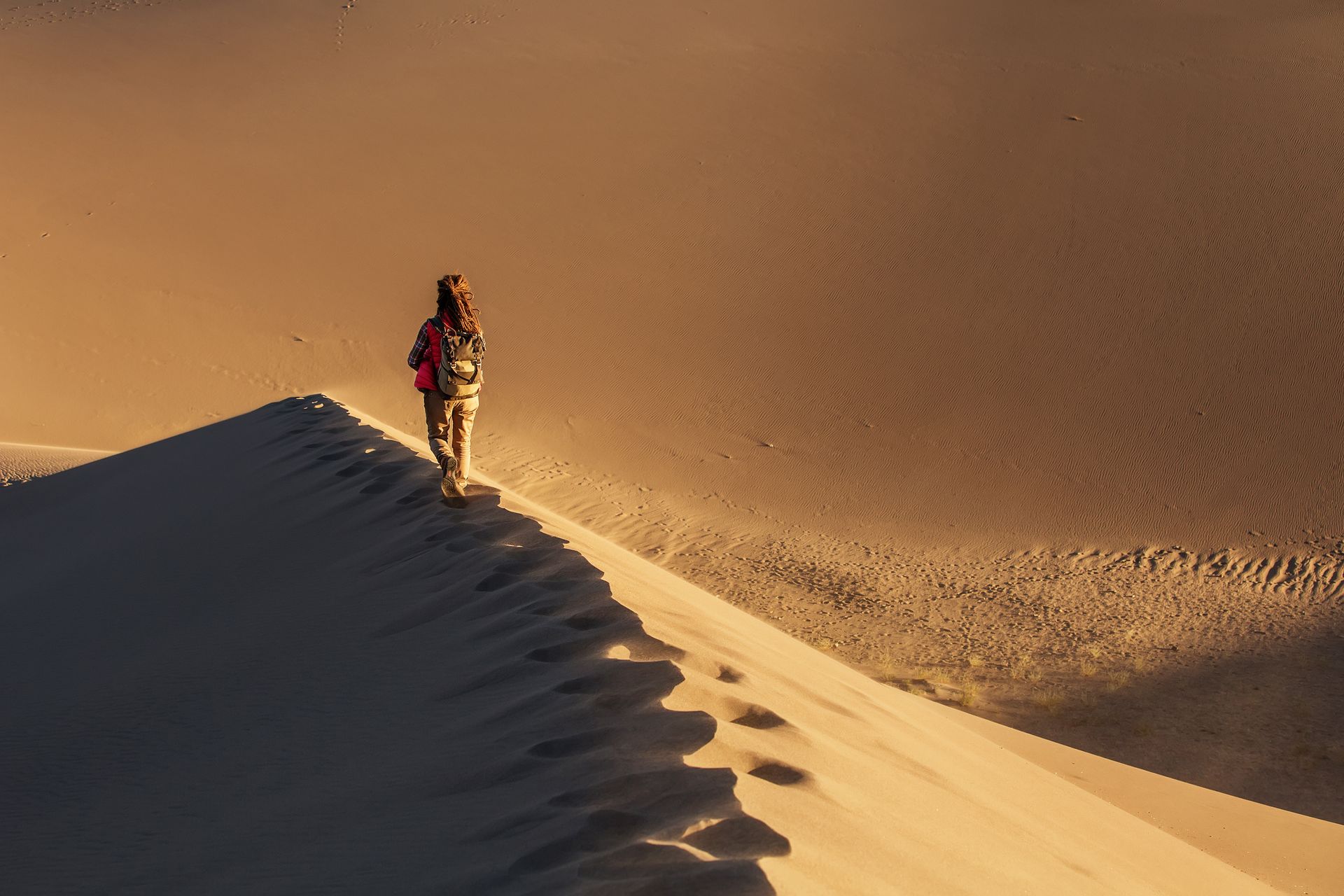 Walker on desert dune ridge at golden hour